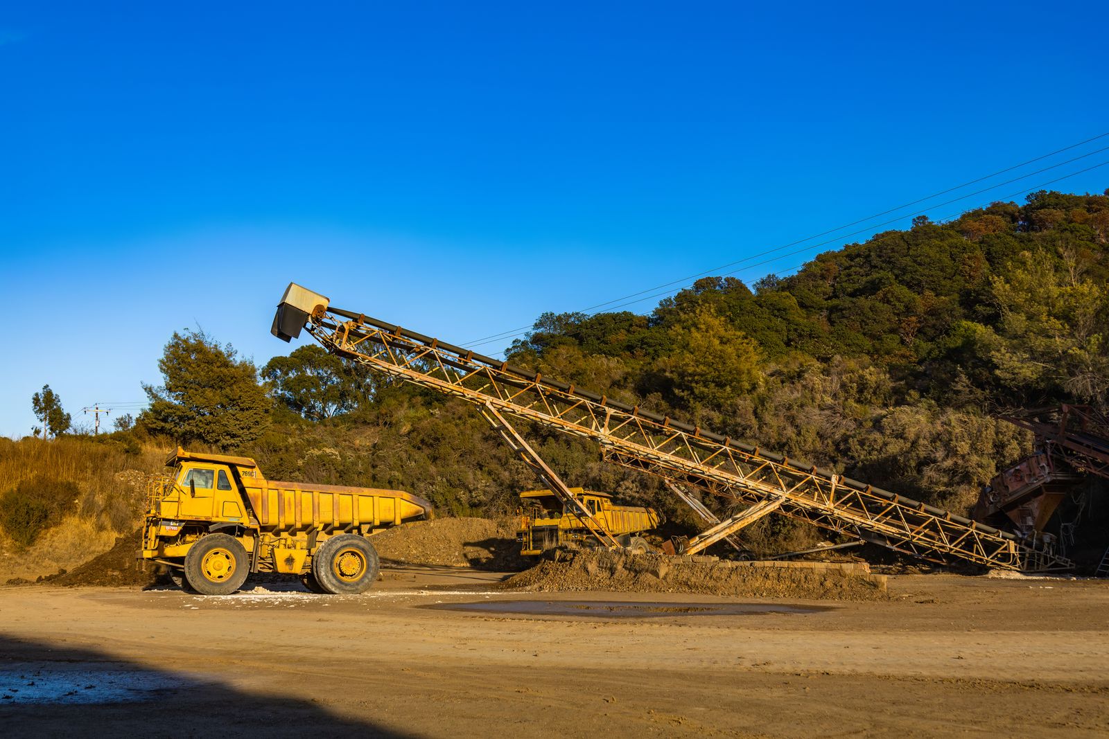 Haul trucks and conveyor equipment operating at a mining site